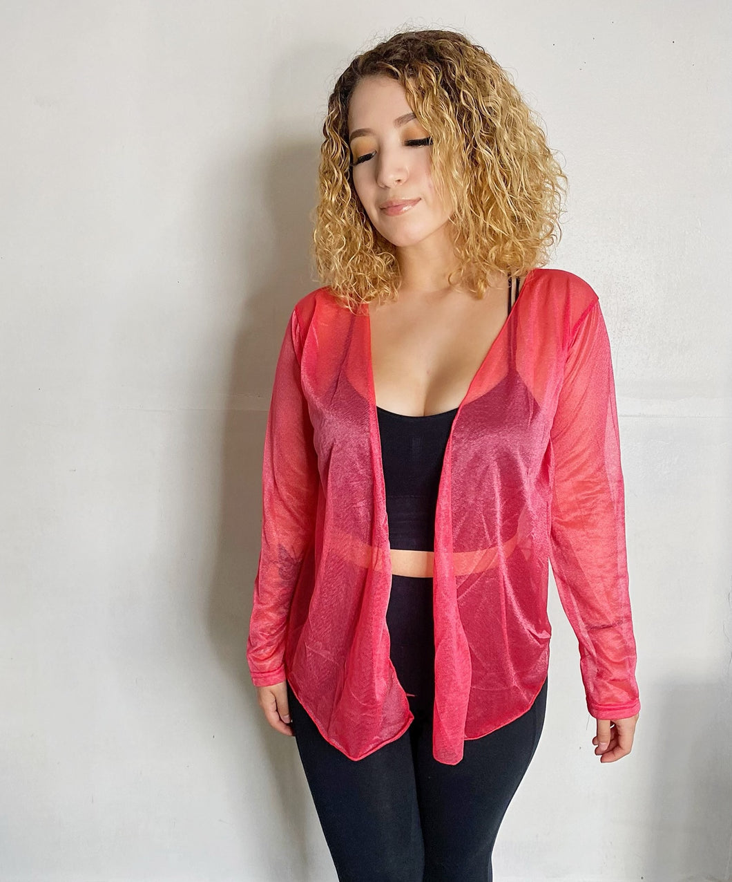 Girl with curly hair wearing a pink cardigan.